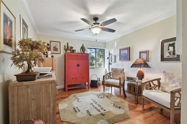 living area with ornamental molding, hardwood / wood-style floors, and ceiling fan