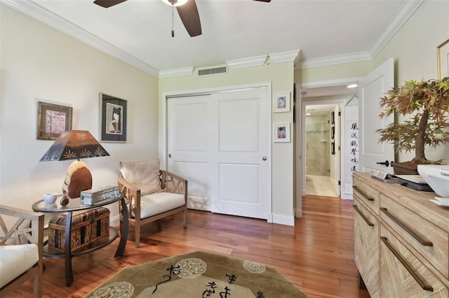 living area with crown molding, dark hardwood / wood-style floors, and ceiling fan