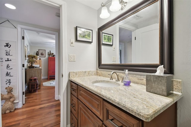 bathroom featuring vanity, ornamental molding, and wood-type flooring