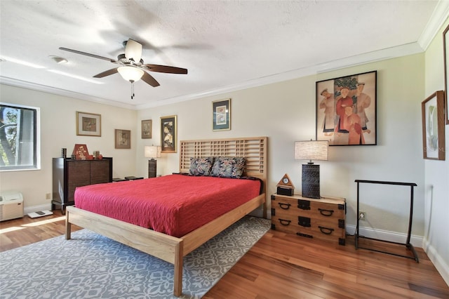 bedroom featuring crown molding, hardwood / wood-style flooring, a textured ceiling, and ceiling fan