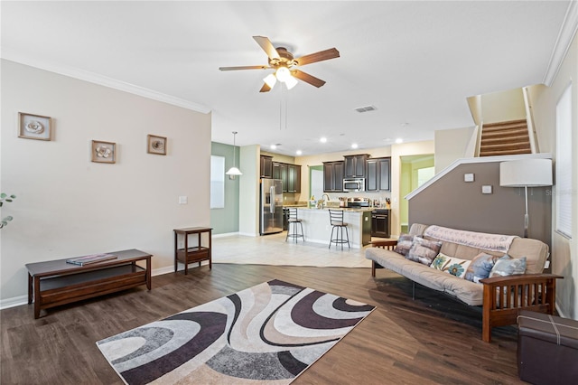 living room with ceiling fan, hardwood / wood-style flooring, sink, and crown molding