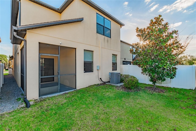 back of property with central air condition unit and a lawn