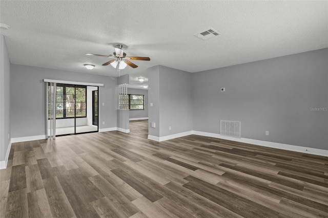 empty room with a textured ceiling, ceiling fan, and dark hardwood / wood-style flooring