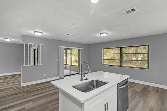 kitchen with white cabinets, a textured ceiling, a kitchen island with sink, dark wood-type flooring, and sink