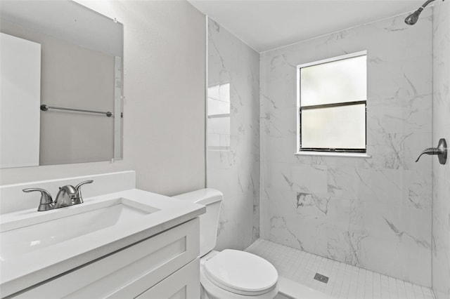 bathroom with toilet, vanity, and tiled shower