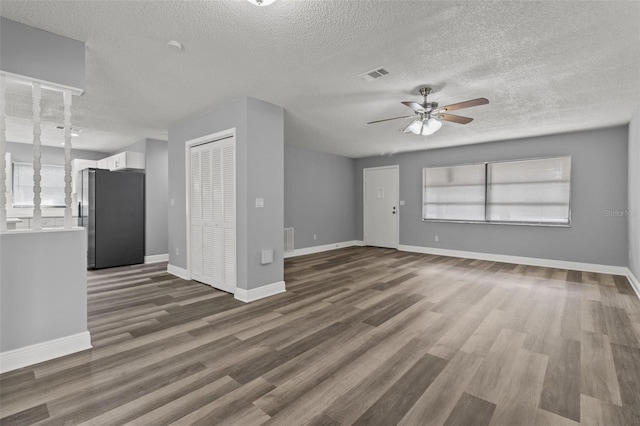 unfurnished living room featuring a textured ceiling, dark wood-type flooring, plenty of natural light, and ceiling fan