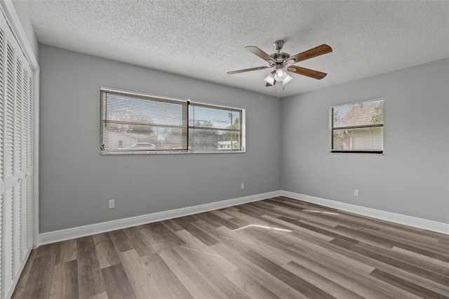 spare room featuring a healthy amount of sunlight, a textured ceiling, and hardwood / wood-style floors