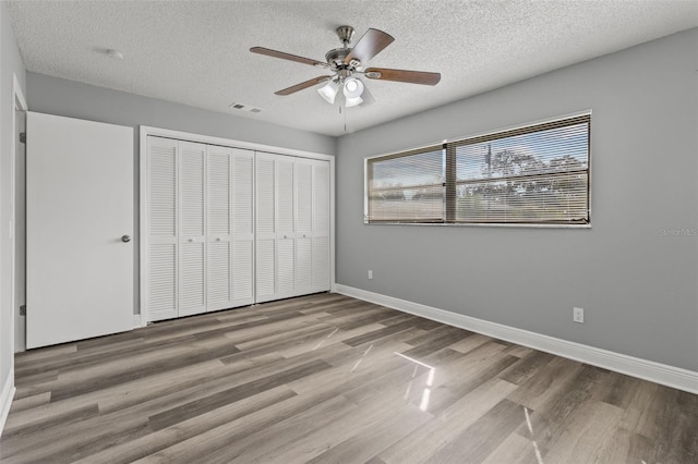 unfurnished bedroom featuring hardwood / wood-style floors, a textured ceiling, and ceiling fan