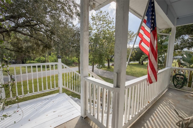 wooden terrace featuring a porch and a lawn