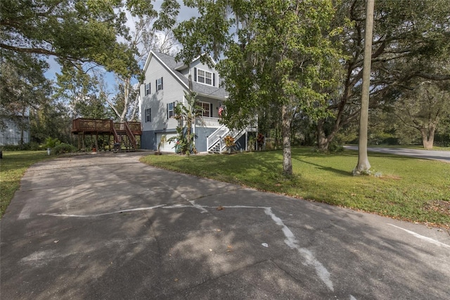 view of front facade with a front yard, a garage, and a wooden deck