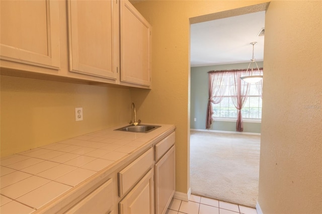 kitchen with light colored carpet, tile countertops, sink, and hanging light fixtures