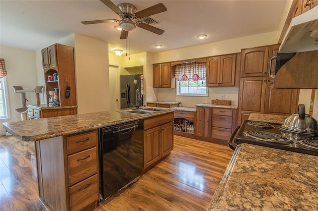 kitchen with ceiling fan, a kitchen island with sink, dark hardwood / wood-style floors, black appliances, and sink