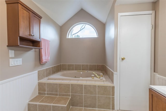 bathroom with vanity, lofted ceiling, and tiled tub