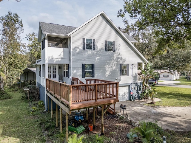 back of property featuring a wooden deck, a lawn, and a garage