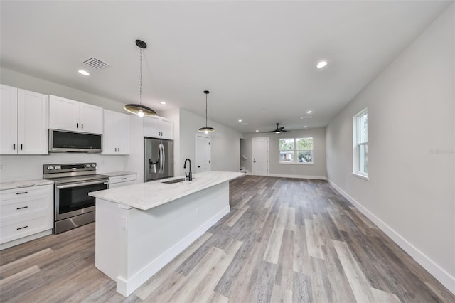 kitchen featuring white cabinets, a center island with sink, appliances with stainless steel finishes, and ceiling fan