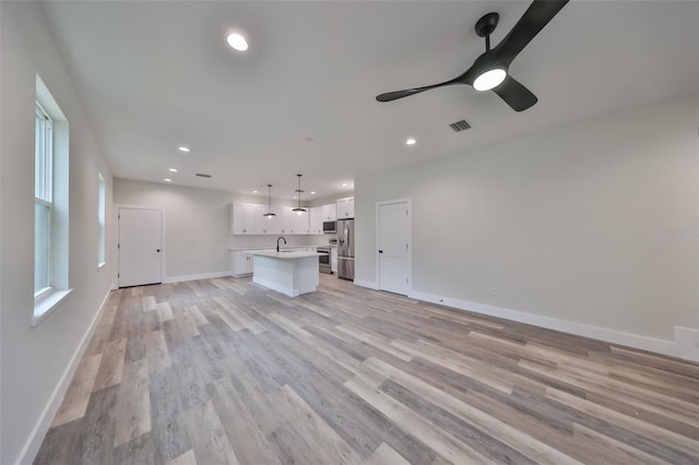 unfurnished living room featuring ceiling fan, light hardwood / wood-style floors, and sink