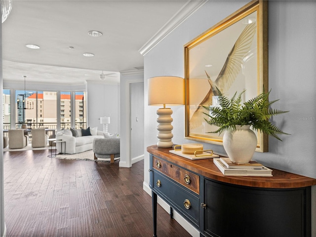 hallway with dark wood-style flooring, crown molding, and baseboards