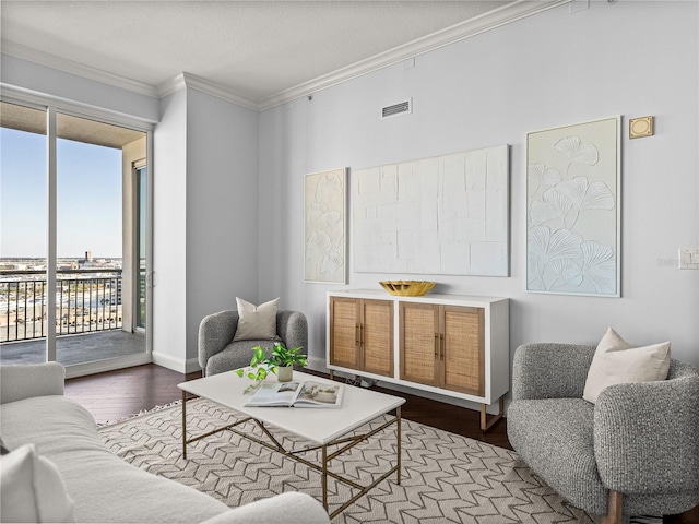 living room with baseboards, visible vents, wood finished floors, and ornamental molding