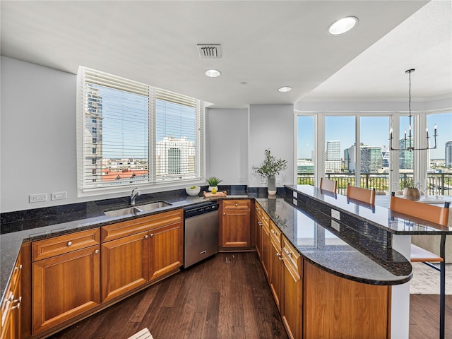 kitchen featuring dark stone countertops, sink, pendant lighting, stainless steel dishwasher, and dark hardwood / wood-style flooring