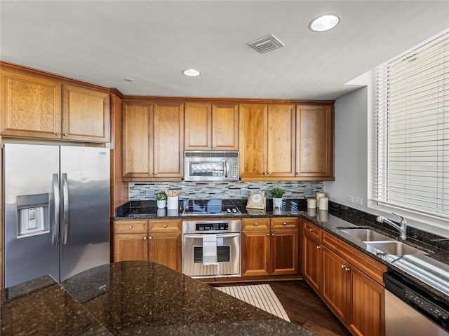 kitchen with stainless steel appliances, dark wood-type flooring, a sink, visible vents, and decorative backsplash