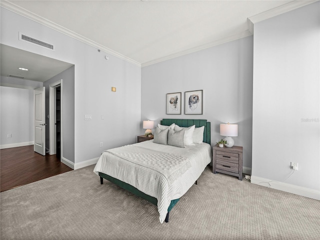 carpeted bedroom with visible vents, crown molding, and baseboards