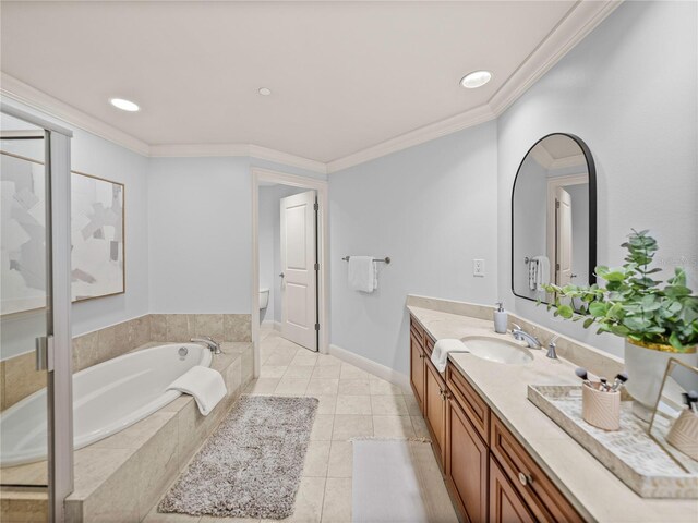 bathroom with tiled bath, toilet, vanity, crown molding, and tile patterned flooring