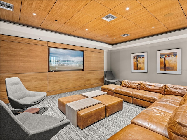 home theater room featuring a tray ceiling, wood ceiling, and visible vents