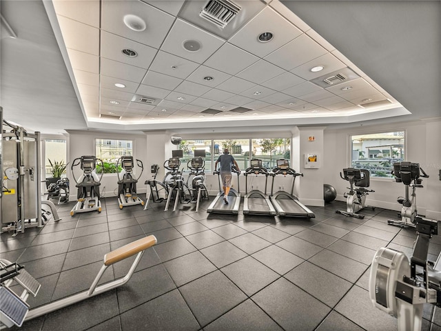 gym featuring a raised ceiling, visible vents, and baseboards