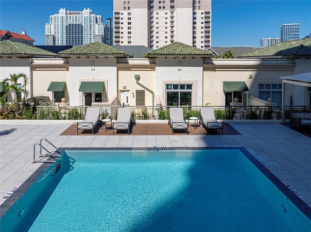 back of house with a view of city, a patio, a community pool, and stucco siding