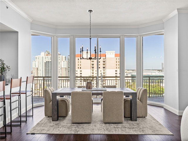 dining room featuring crown molding, a view of city, dark wood-style flooring, and a notable chandelier