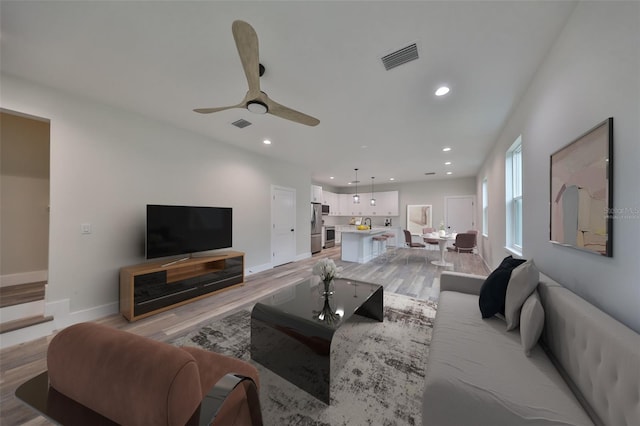 living room featuring ceiling fan and light hardwood / wood-style floors