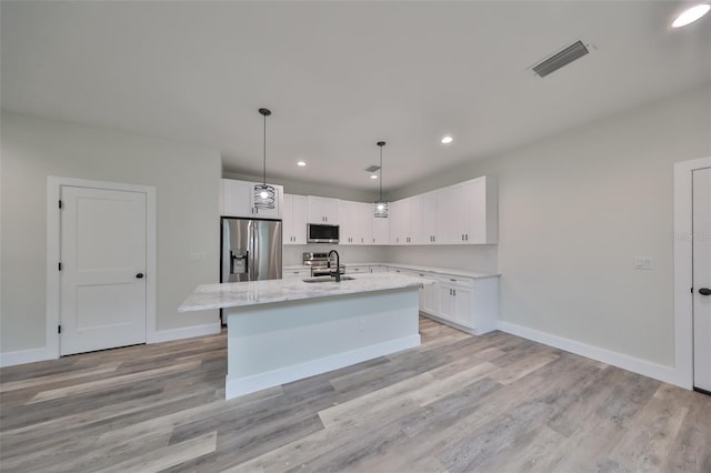 kitchen featuring light hardwood / wood-style flooring, an island with sink, white cabinets, appliances with stainless steel finishes, and sink