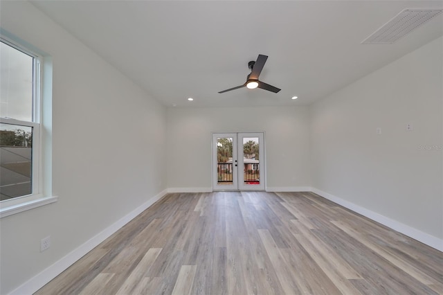 empty room with ceiling fan, light hardwood / wood-style flooring, and french doors