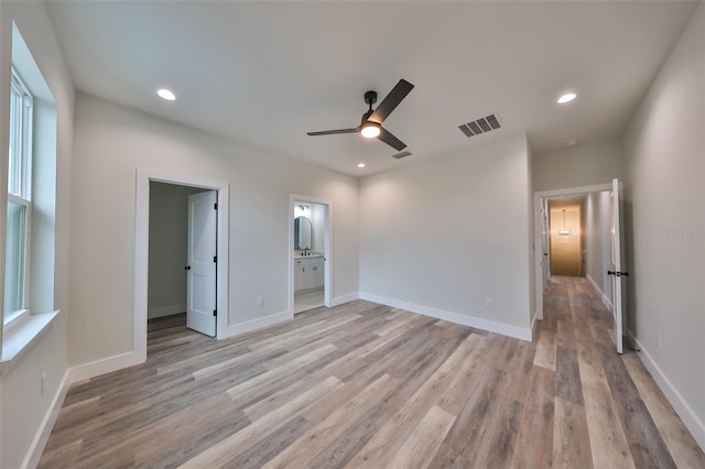 unfurnished bedroom with multiple windows, ceiling fan, light hardwood / wood-style floors, and connected bathroom