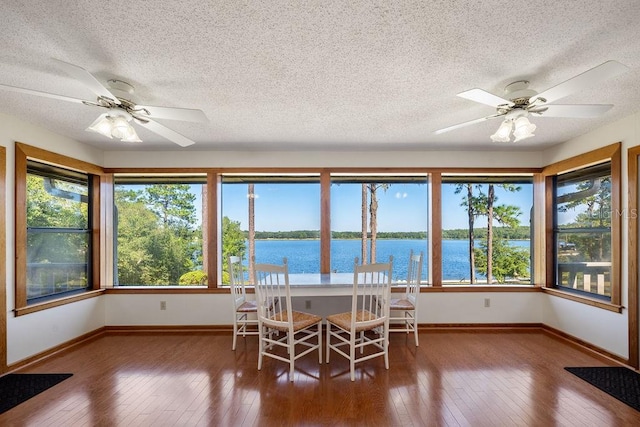 unfurnished dining area featuring a textured ceiling, a water view, and dark hardwood / wood-style flooring