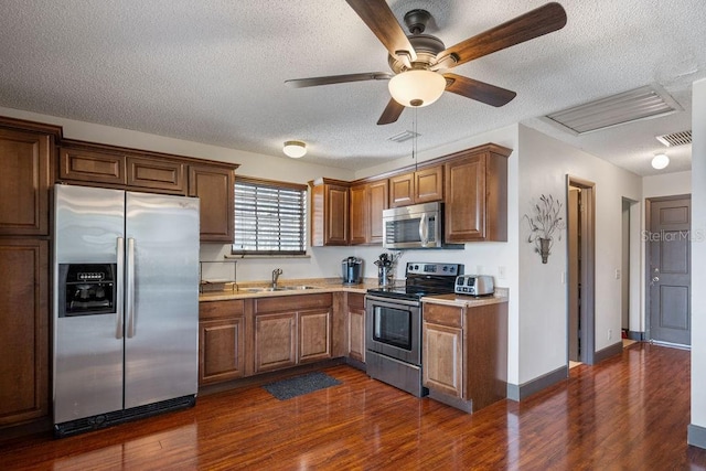 kitchen featuring dark wood-type flooring, ceiling fan, stainless steel appliances, and a textured ceiling