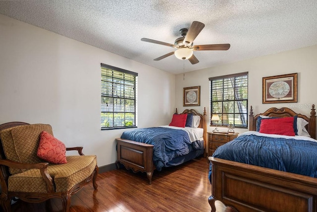 bedroom featuring multiple windows, dark hardwood / wood-style floors, a textured ceiling, and ceiling fan