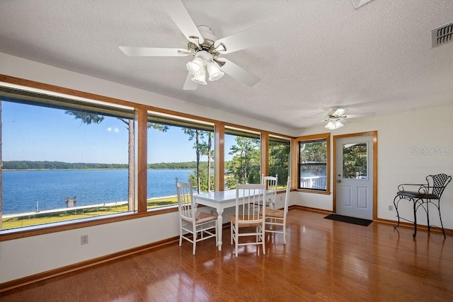 sunroom / solarium featuring a water view and ceiling fan