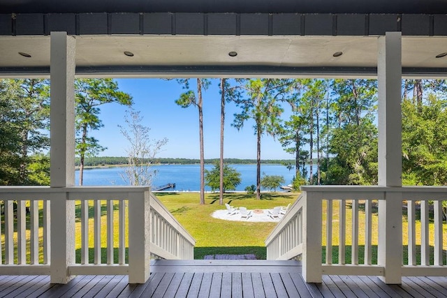 deck with a water view and a lawn