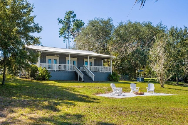 view of front of property with covered porch, a front lawn, and a fire pit