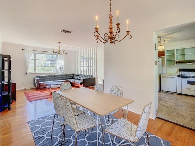 dining space with light hardwood / wood-style floors and ceiling fan with notable chandelier