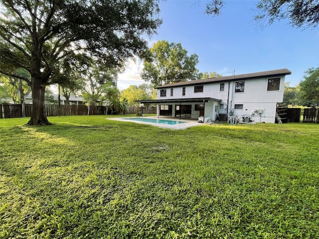 rear view of house featuring a patio area, a fenced in pool, and a lawn