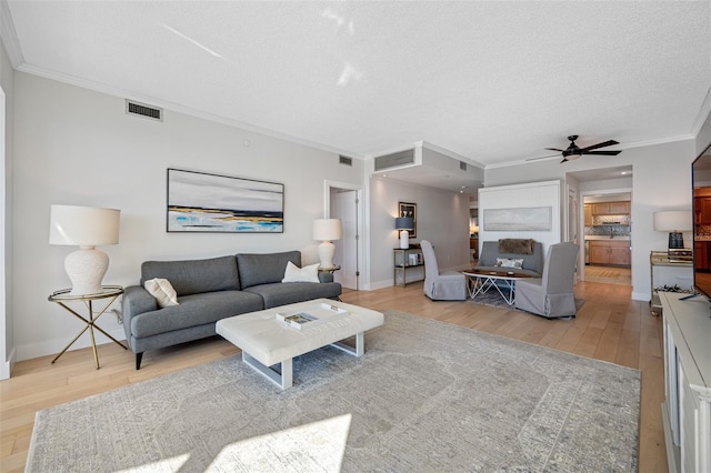 living room featuring ornamental molding, a textured ceiling, light hardwood / wood-style floors, and ceiling fan