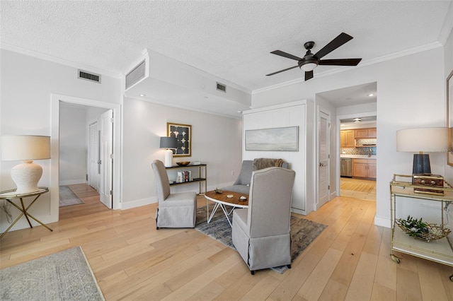 living area featuring light hardwood / wood-style floors, a textured ceiling, ornamental molding, and ceiling fan