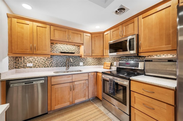 kitchen with light tile patterned floors, stainless steel appliances, tasteful backsplash, and sink