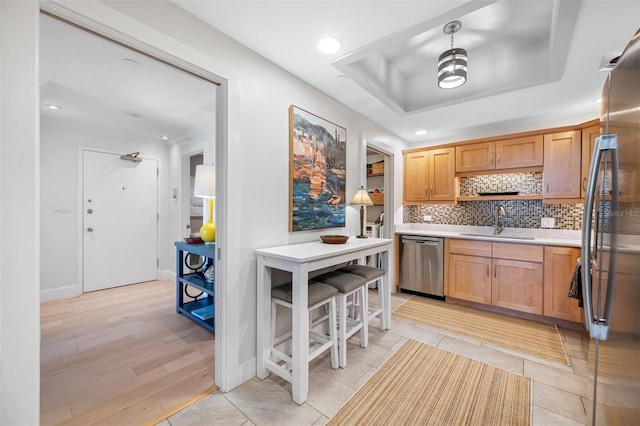 kitchen featuring decorative backsplash, light hardwood / wood-style flooring, sink, a raised ceiling, and appliances with stainless steel finishes