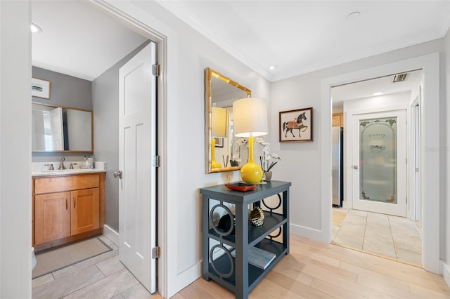 corridor featuring ornamental molding, sink, and light hardwood / wood-style floors