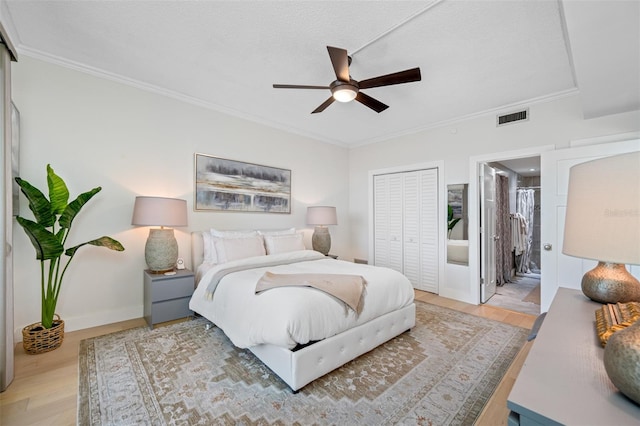 bedroom featuring connected bathroom, a closet, light hardwood / wood-style flooring, ornamental molding, and ceiling fan