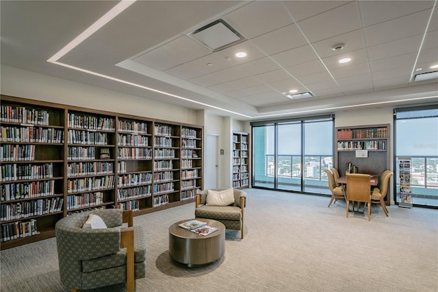 living area featuring a raised ceiling, carpet floors, and plenty of natural light