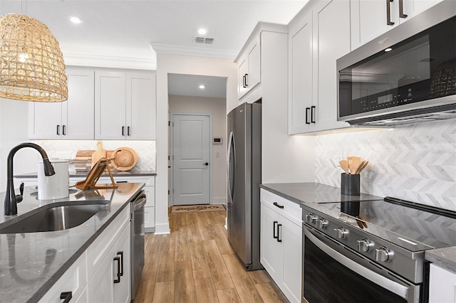 kitchen with white cabinetry, light hardwood / wood-style floors, stainless steel appliances, and pendant lighting